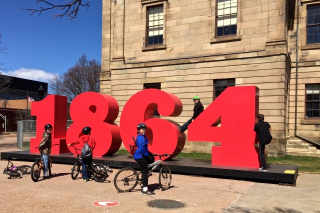 Kids on bikes around the 1864 sign in downtown Charlottetown.